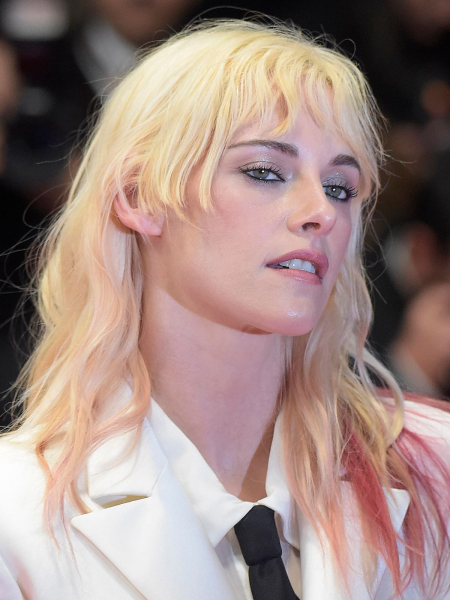 Kristen Stewart posing in a white suit and black tie